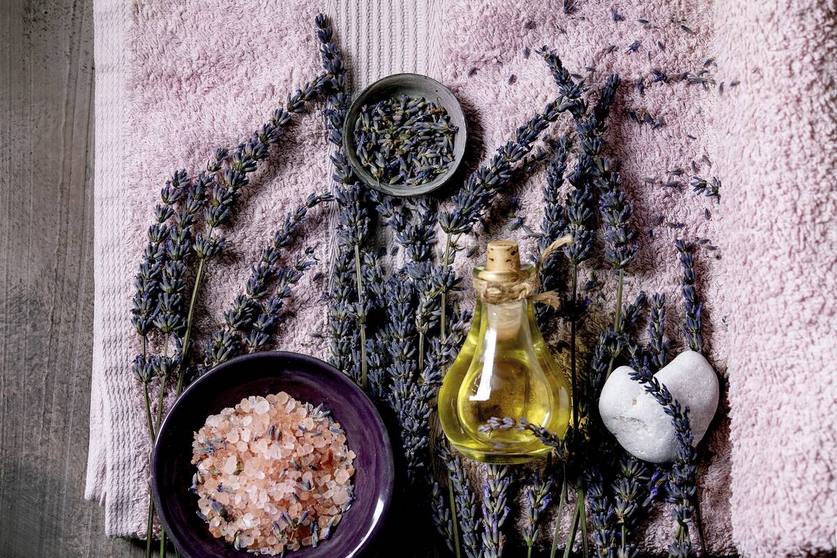 SPA concept. Flat lay of fresh and dry lavender flowers. essential oil. pink salt. stones as heart shape. aromatic candle on pink bath towel over textured background.