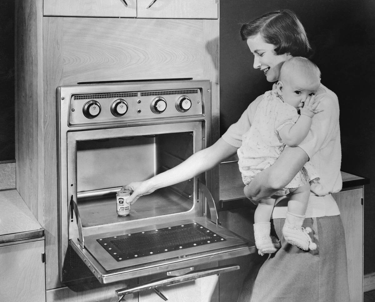 Woman with Baby Heating Up Food in New Oven