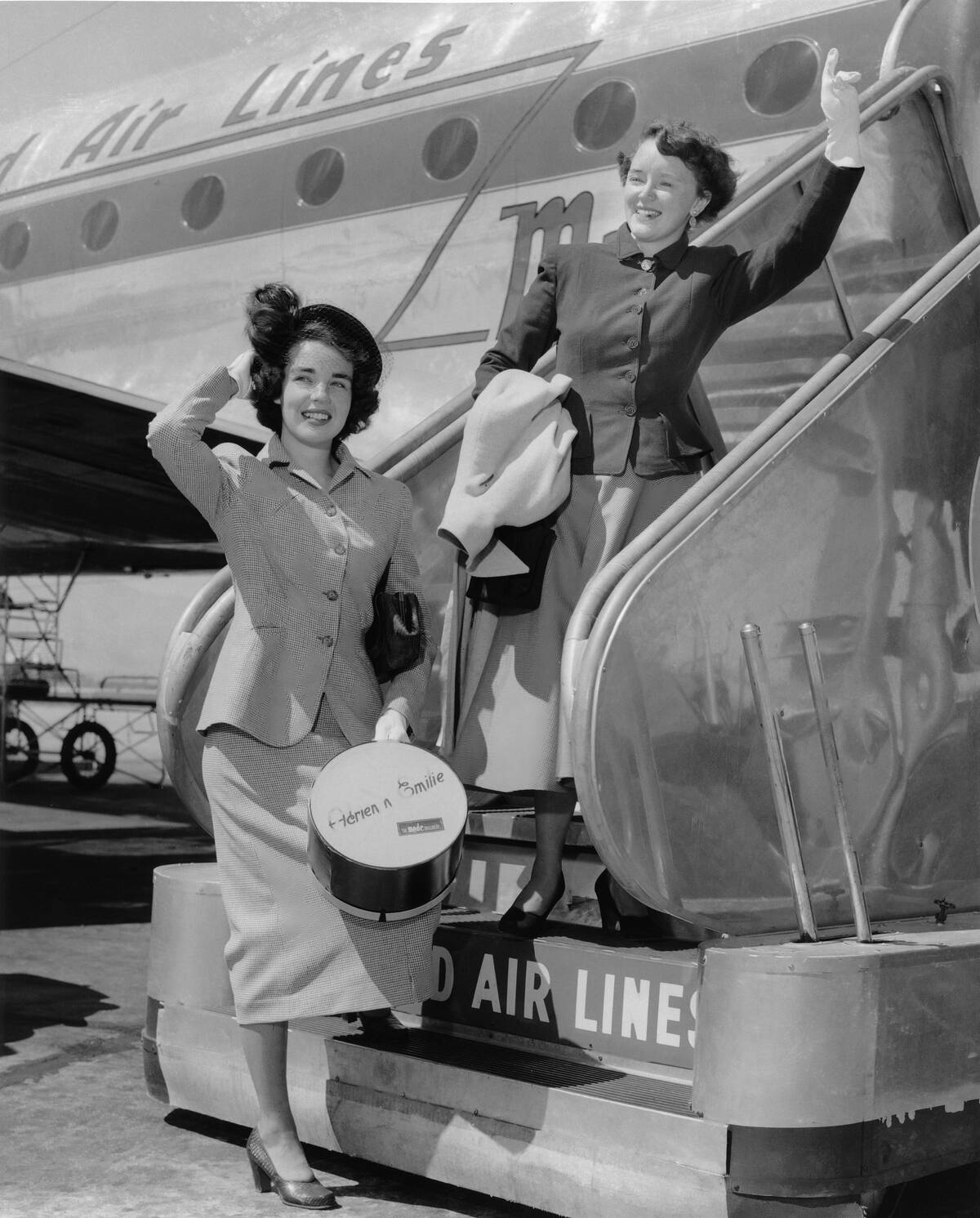 Two young ladies boarding an airliner in the 50s