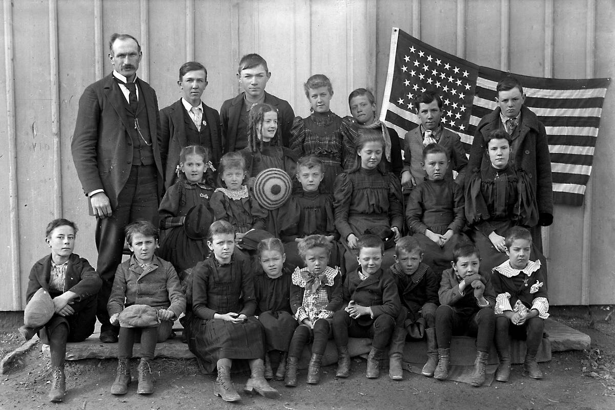 A teacher poses with the students of his one room schoolhouse. ca. 1900