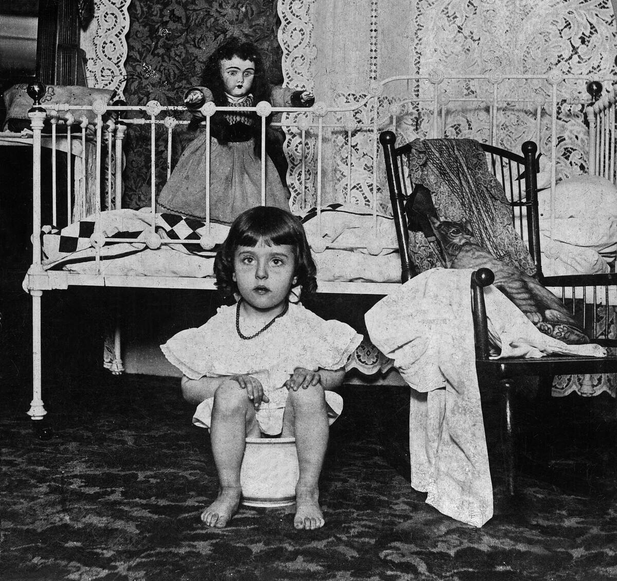 Little girl on chamber pot in her bedroom c. 1900