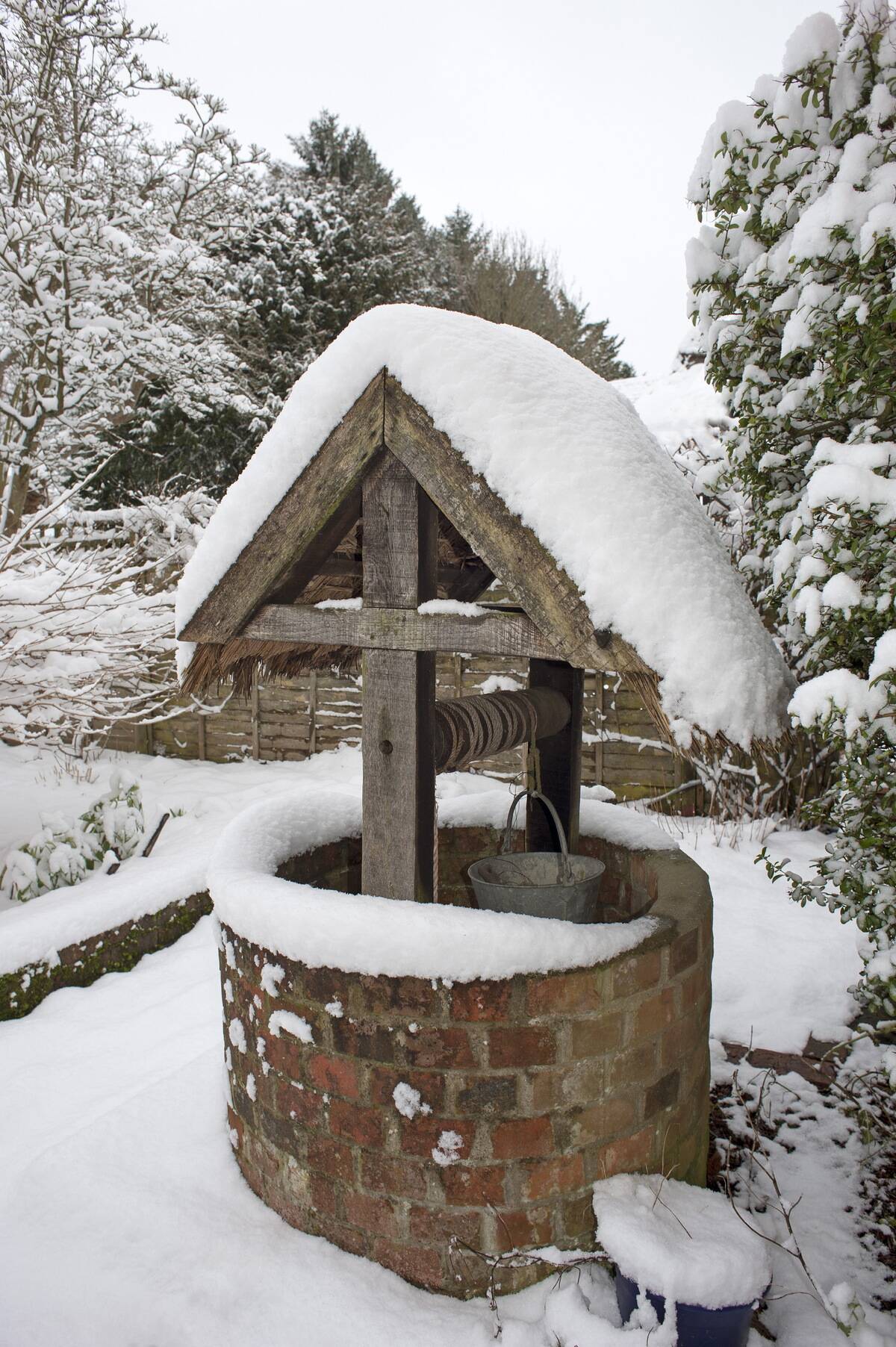 Thatched well covered in snow in a Hampshire England garden