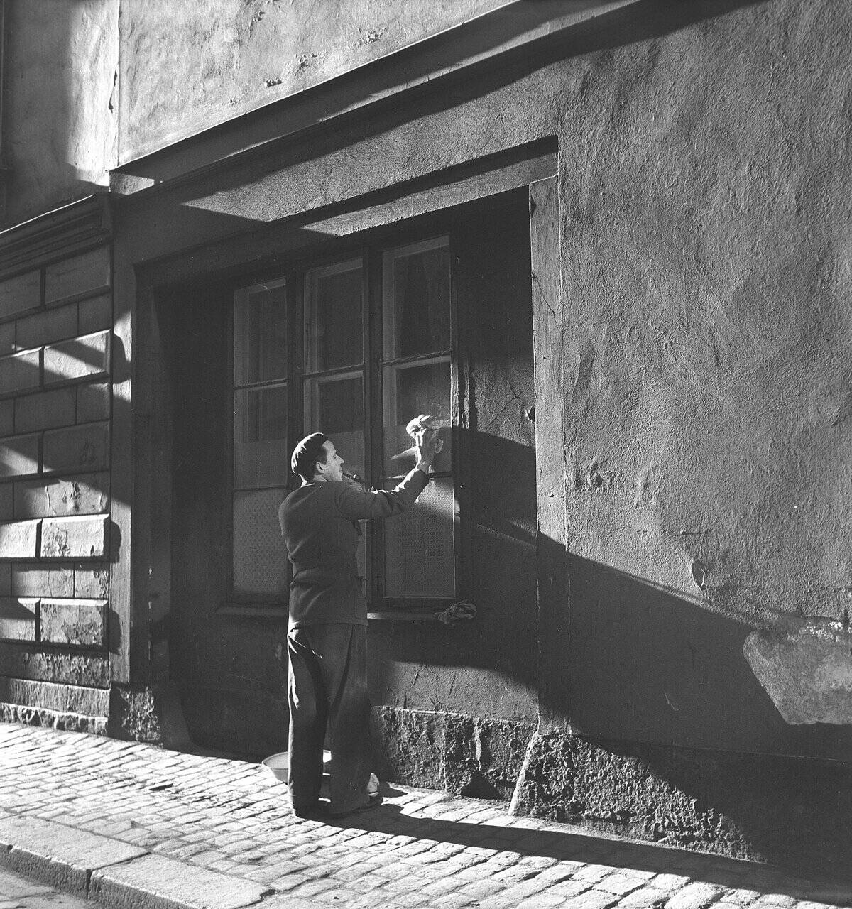 Västra Kyrkogata in Klarakvarter's classic newspaper quarter. A shop owner cleans the windows. The cob...