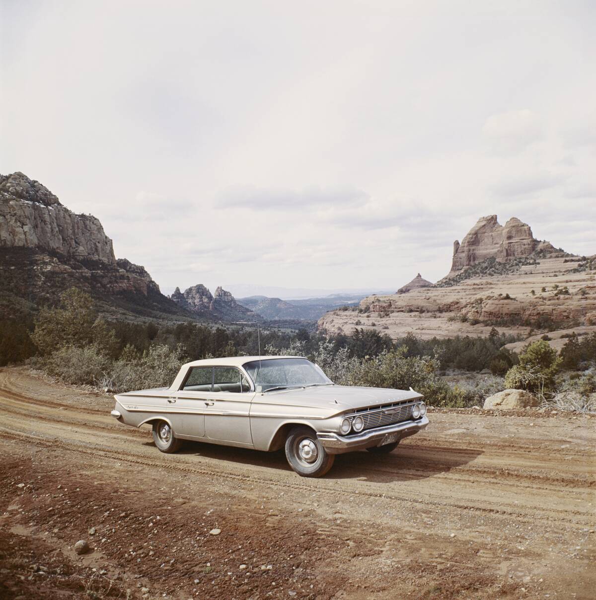 Car on dirt track with mountains in background