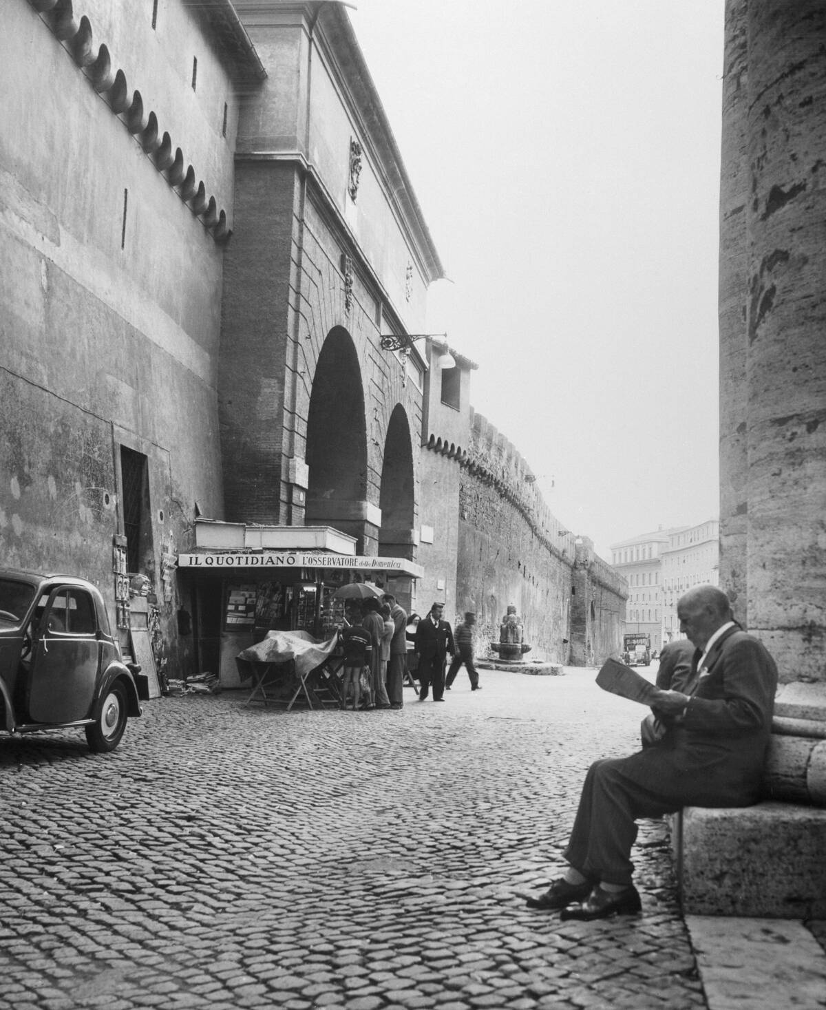 Man Reading Newspaper by Cobblestone Street