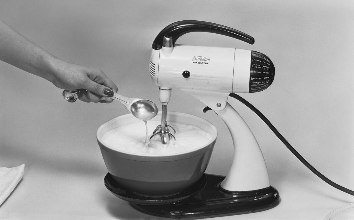 Whisking dairy product in bowl by electric whisk