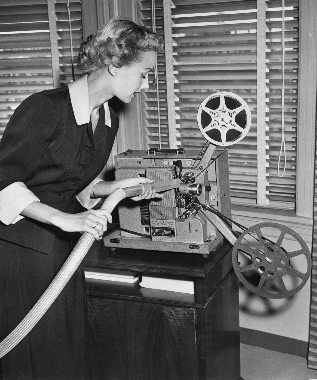 Woman Cleaning Film Projector with Vacuum
