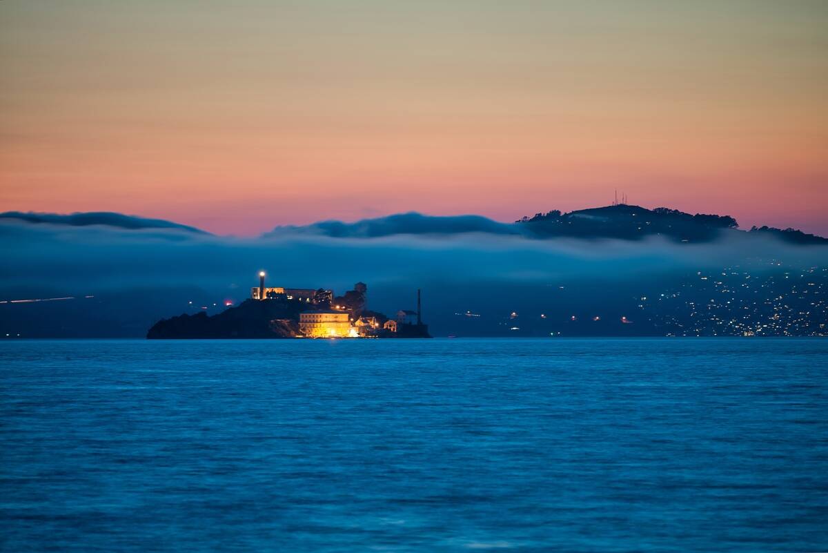 Alcatraz Island at sunset surrounded by fog and mountains