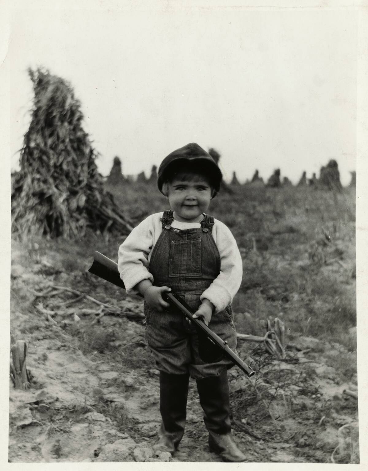 Young Toddler Holding Toy Gun in Agricultural Field