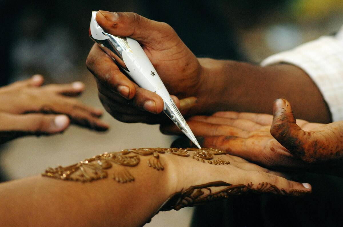 An Indian man applies henna on the hands