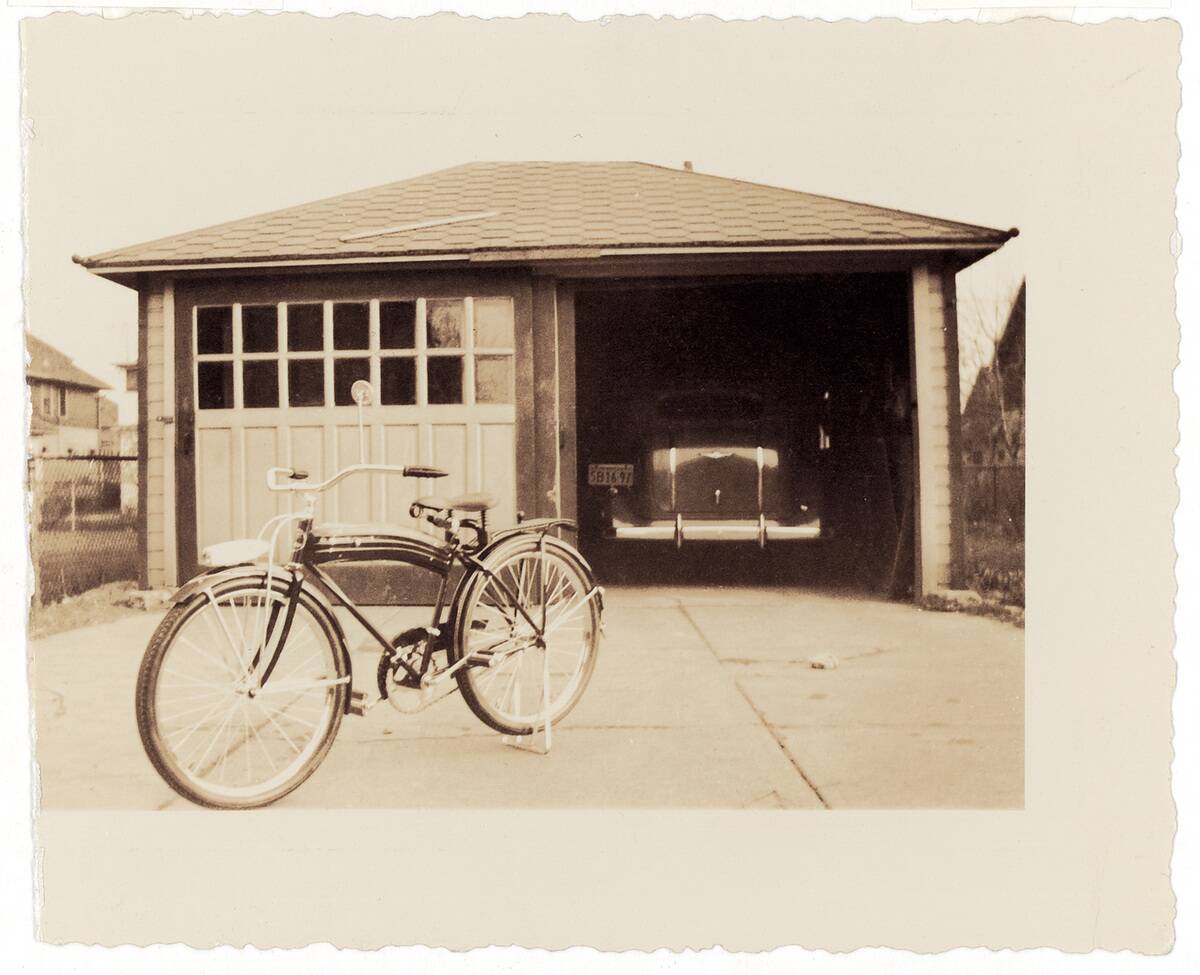 Garage, in the front a bicycle. Photograph. Around 1930.