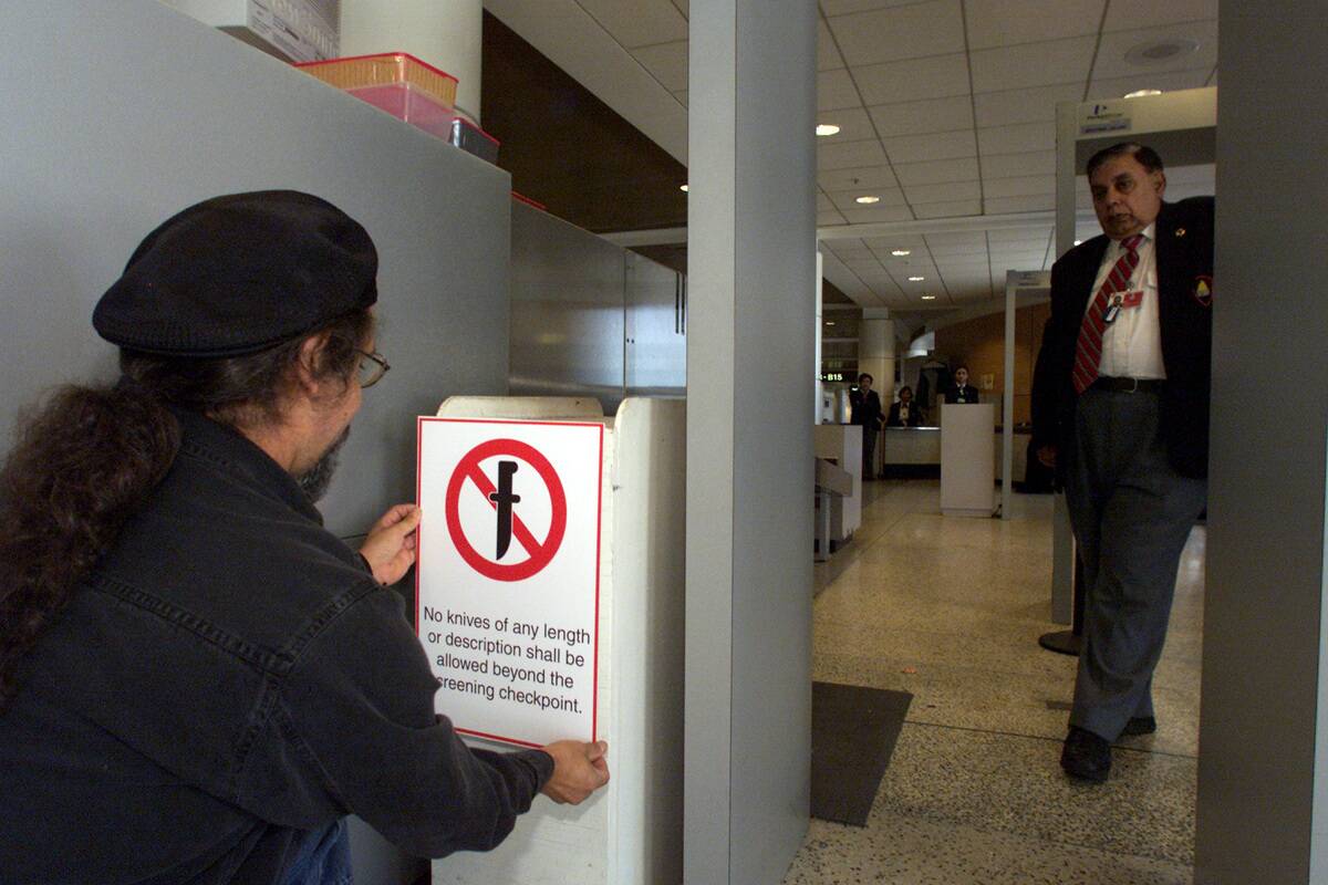 Port of Seattle employee Frank Irlanda hangs a sign warning that knives of any length are prohibited