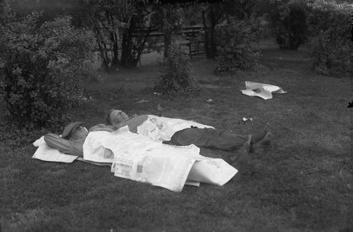 Two man sleeping in park covered with newspapers