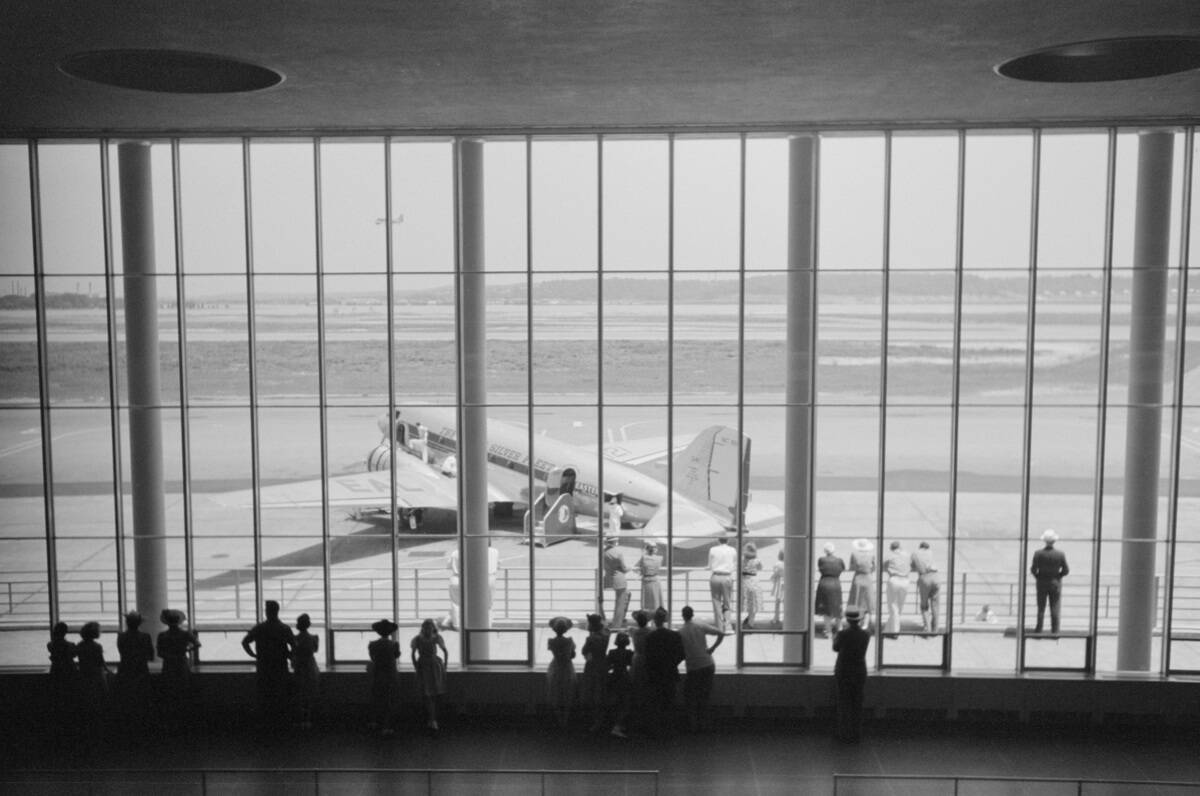 Visitors Watching Airplanes through Window of Main Waiting Room at Municipal Airport