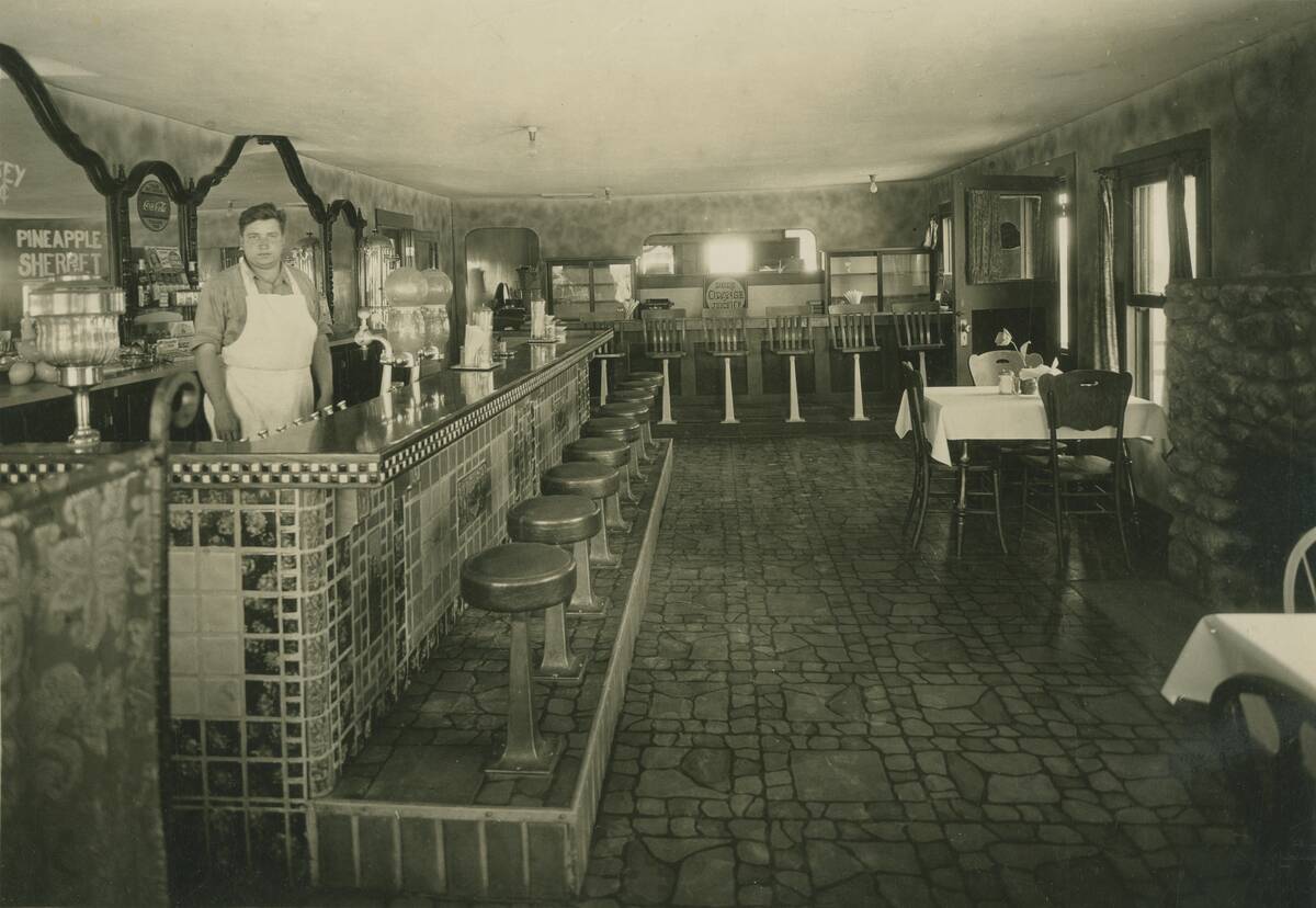 Waiter posing behind counter in restaurant.