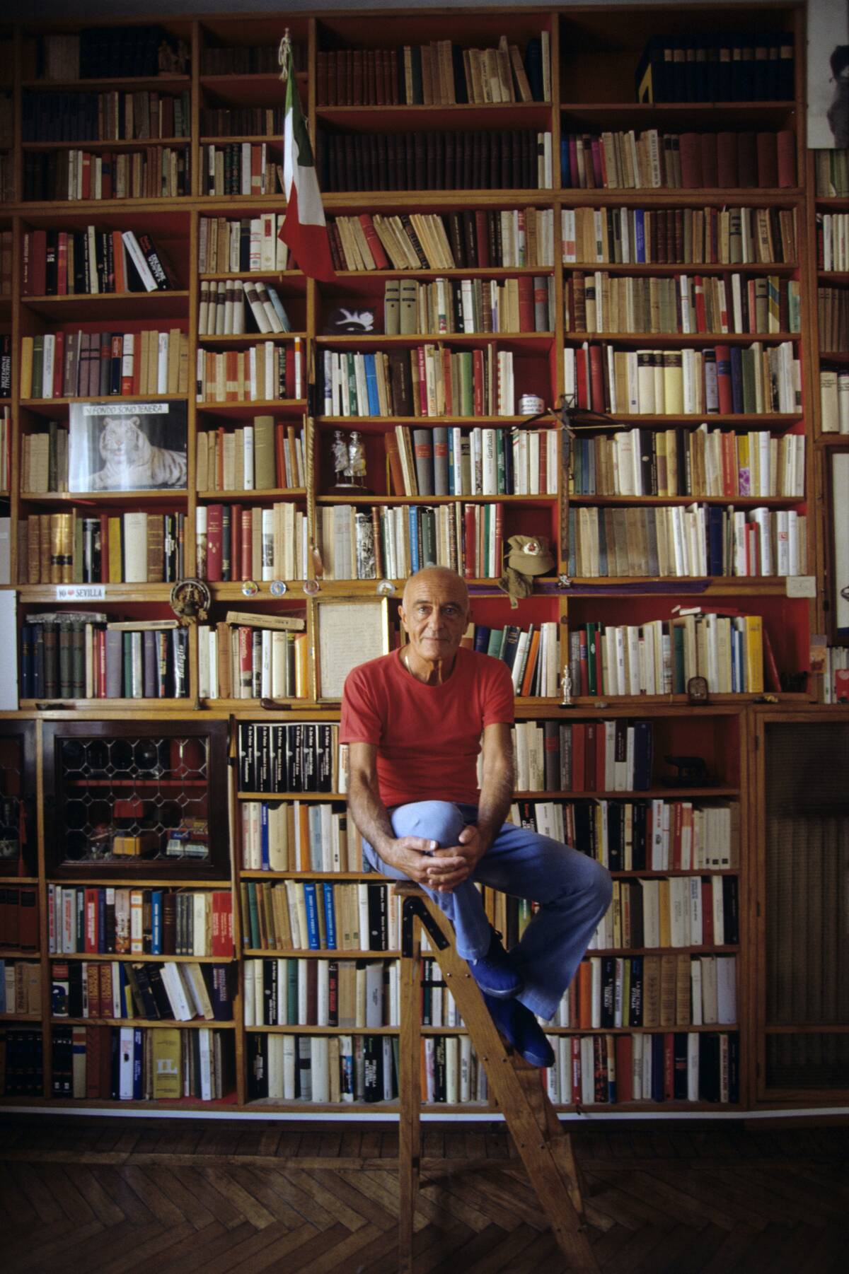 Mino Milani sitting before his library
