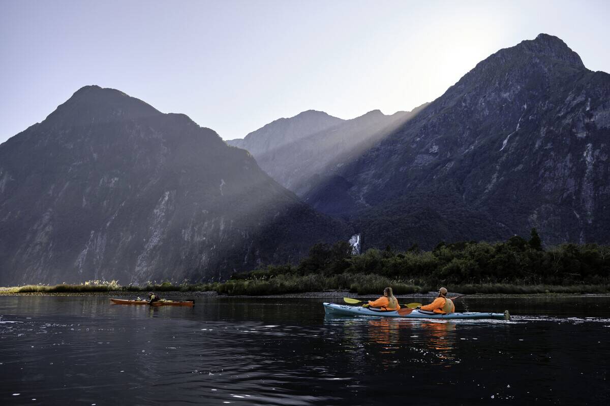 Tourists kayaking in the waters of the Milford Sound when