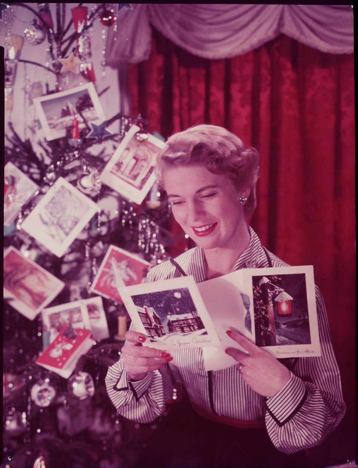 Woman reading Christmas cards, c. 1950.